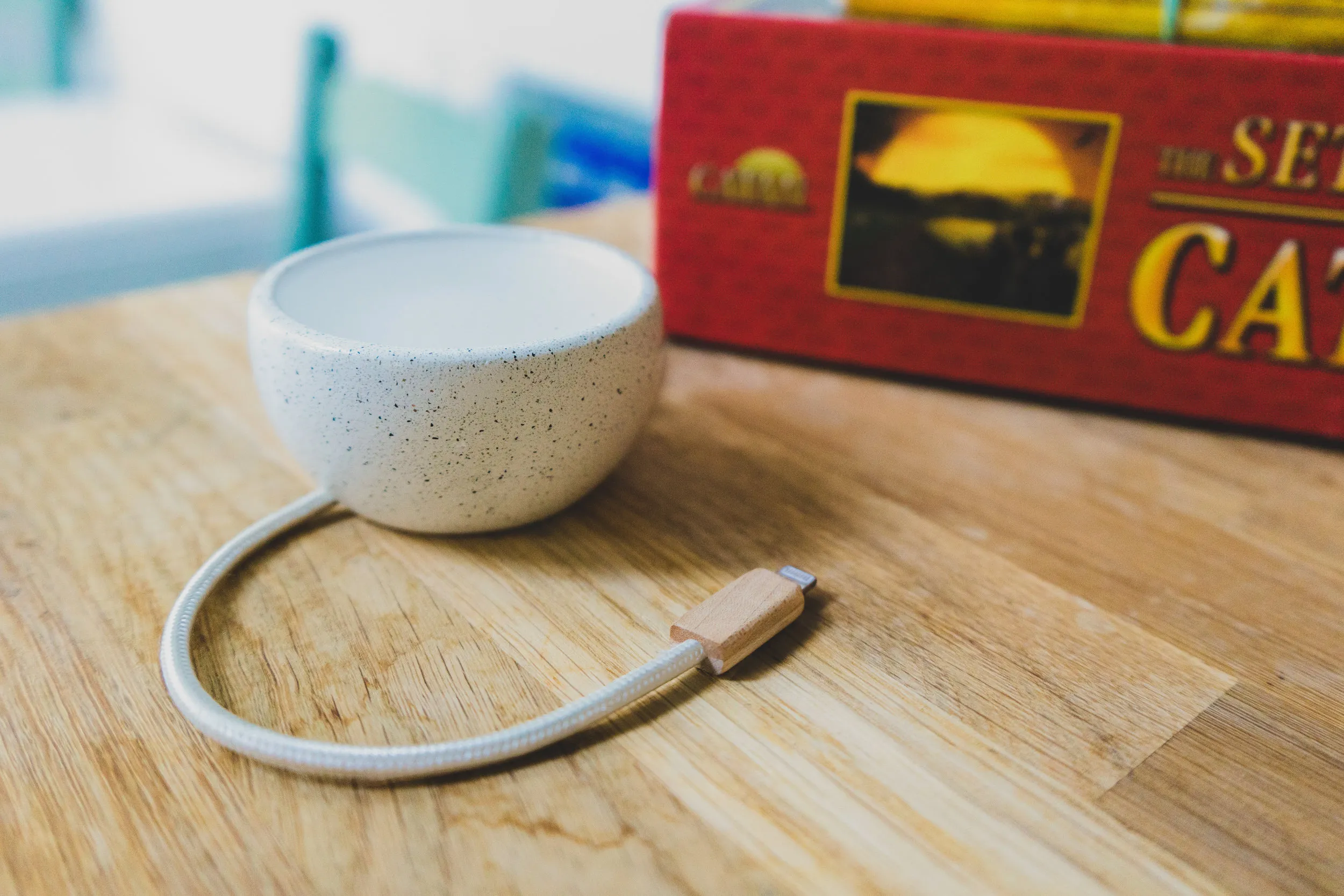 The Candle device: a speckled ceramic dome with a braided cable and a wooden connector, sitting on a kitchen table